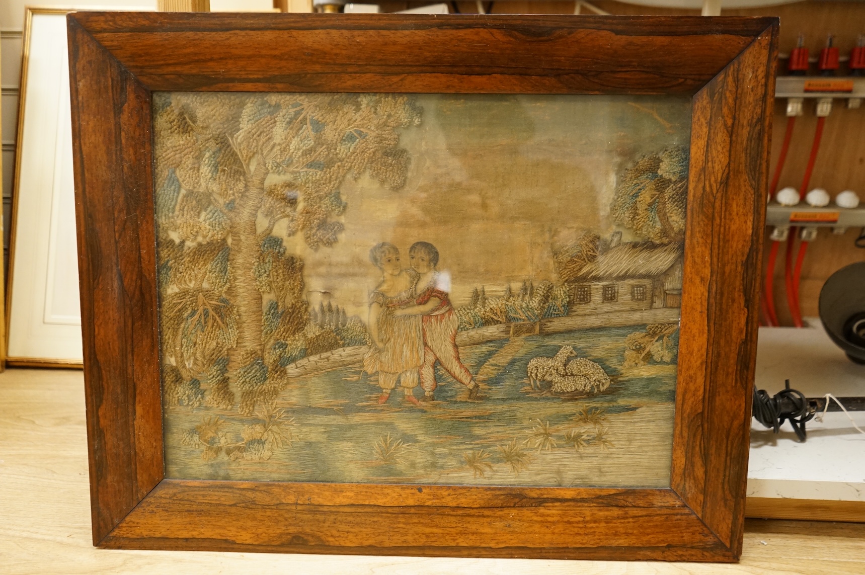 Two early 19th century embroidered silk tapestries depicting figures in landscapes, one framed, largest 52cm high